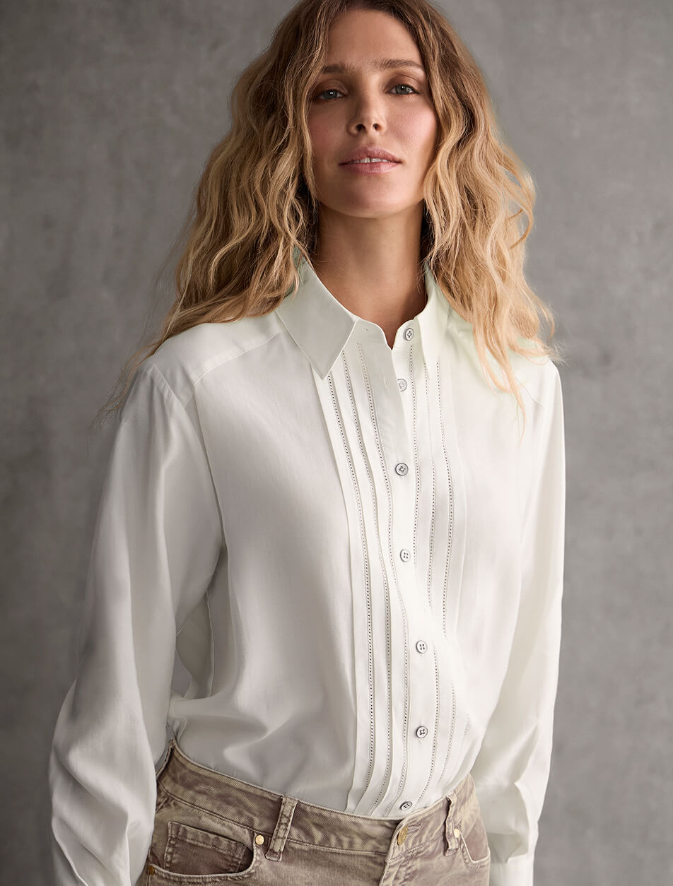 A female model wearing a white pleated dress shirt